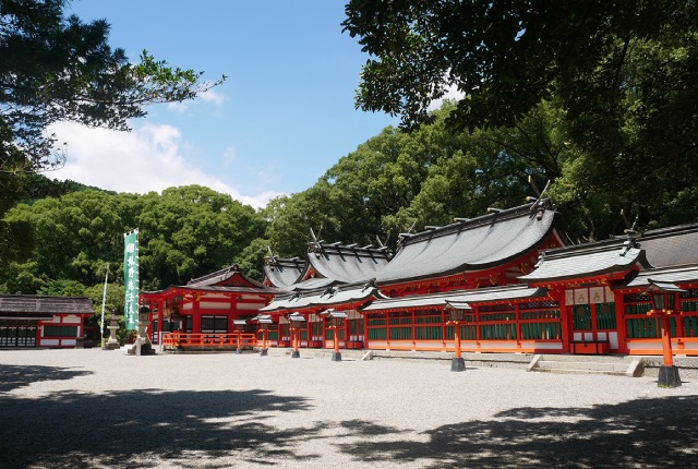 熊野速玉大社の本殿。赤い建物が緑の木々に囲まれ、美しい伝統的な神社の景観。